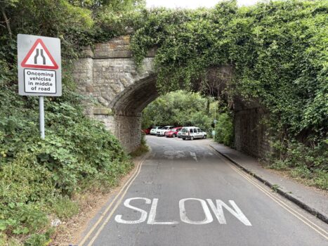 Image shows narrow highway near the Bird in Hand pub, where the exit/entry to the Greenway is located